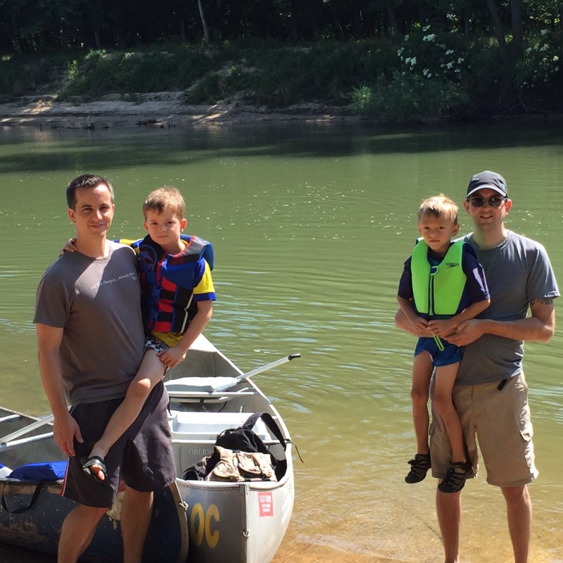 Two dads with their sons prepping for a canoe trip